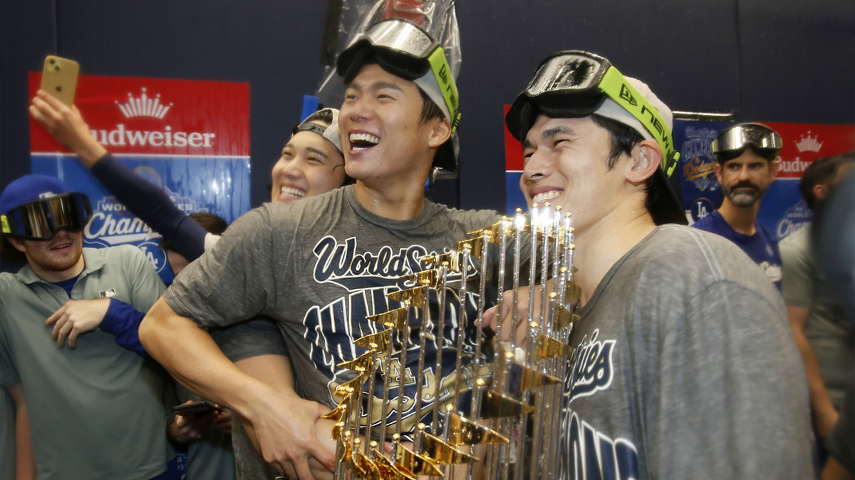 Los Angeles Dodgers two-way player Shohei Ohtani (17) and pitcher Yoshinobu Yamamoto (18) and pitcher Roki Sasaki (11) celebrate with the Commissioner's Trophy in the clubhouse after defeating the Toronto Blue Jays in the 2025 MLB World Series at Rogers Centre. Mandatory Credit: John E. Sokolowski-Imagn Images