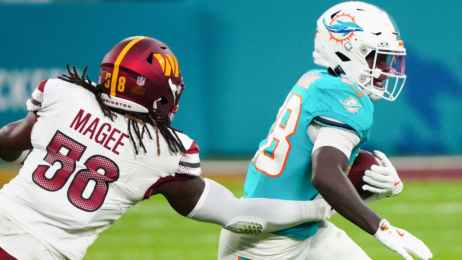 Miami Dolphins running back De'Von Achane (28) carries the ball defended by Washington Commanders linebacker Jordan Magee (58) in the second quarter during the 2025 NFL Madrid Game at Santiago Bernabeu Stadium