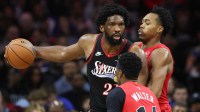 Philadelphia 76ers center Joel Embiid (21) controls the ball against Toronto Raptors forward Scottie Barnes (4) and guard Ja'Kobe Walter (14) during the third quarter at Xfinity Mobile Arena.