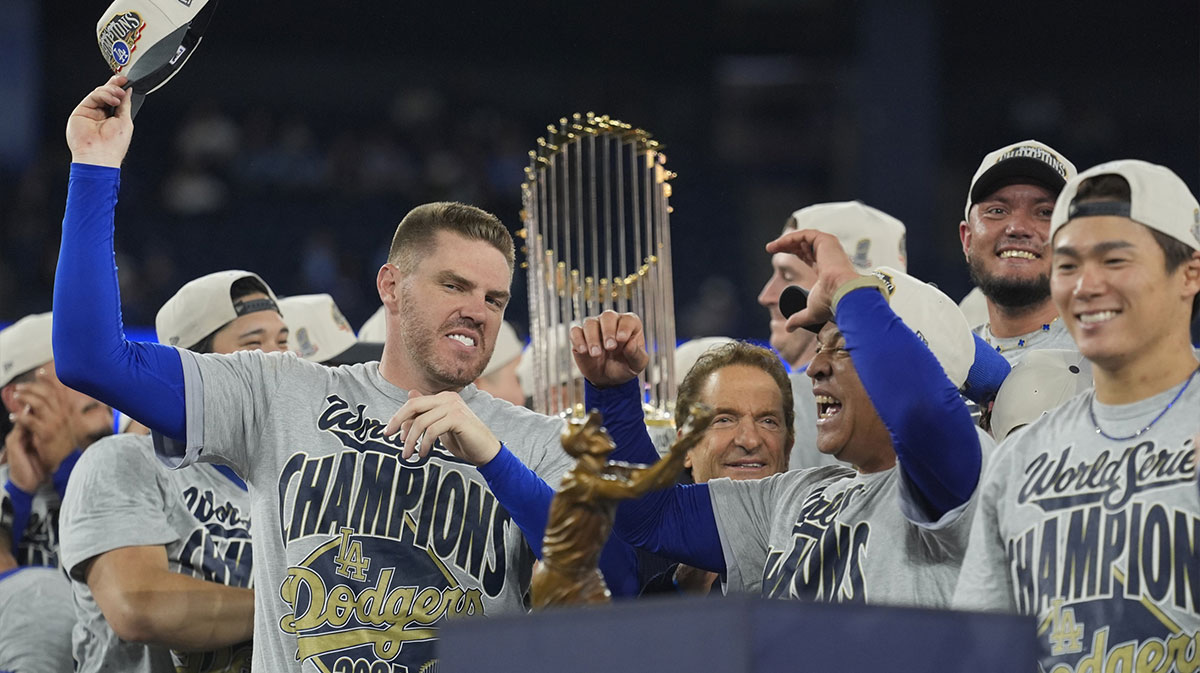 Los Angeles Dodgers first baseman Freddie Freeman (5) and manager Dave Roberts (30) celebrate on the podium after defeating the Toronto Blue Jays in the 2025 MLB World Series at Rogers Centre.