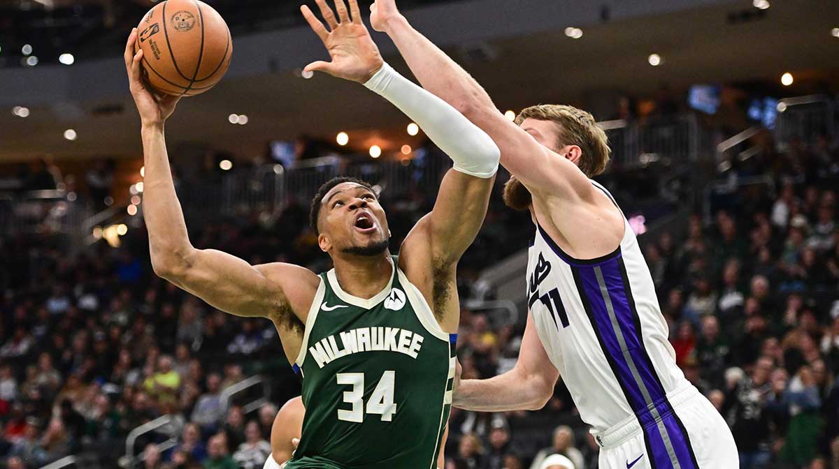 Milwaukee Bucks forward Giannis Antetokounmpo (34) shoots the ball against Sacramento Kings center Domantas Sabonis (11) (obscured) in the second quarter at Fiserv Forum.