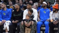 Milwaukee Bucks guard Damian Lillard (0) sits on the bench with Milwaukee Bucks forward Giannis Antetokounmpo (34) and his kids Liam and Maverick during the first half against the Detroit Pistons at American Family Field.
