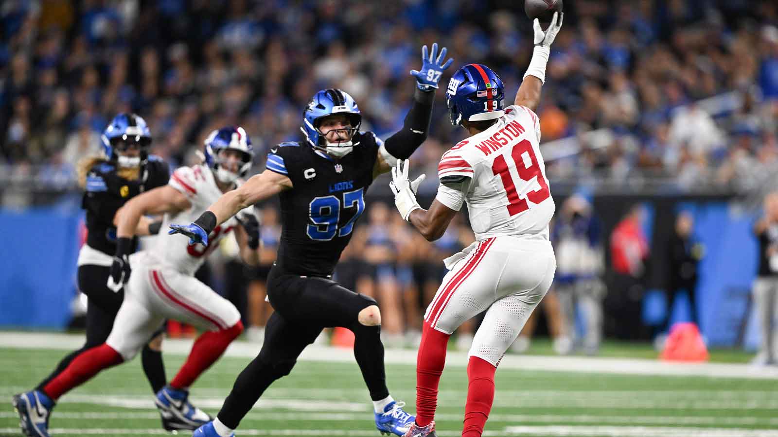 New York Giants quarterback Jameis Winston (19) throws an interception while being defended by Detroit Lions edge Aidan Hutchinson (97) in the fourth quarter at Ford Field.