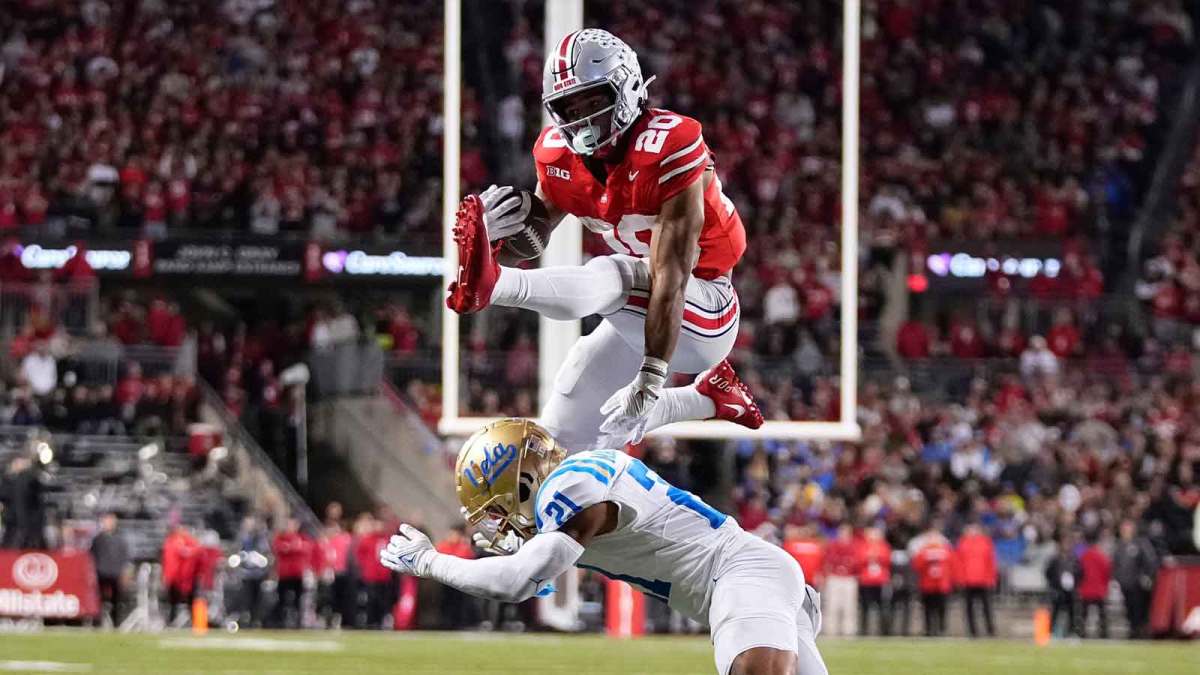 Ohio State Buckeyes running back James Peoples (20) hurdles UCLA Bruins defensive back Cole Martin (21) on his way to scoring a touchdown during the NCAA football game at Ohio Stadium in Columbus on Nov. 15, 2025.