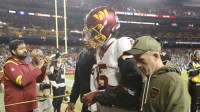 Washington Commanders quarterback Jayden Daniels (5) is helped off the field after an injury during the second half against the Seattle Seahawks at Northwest Stadium.
