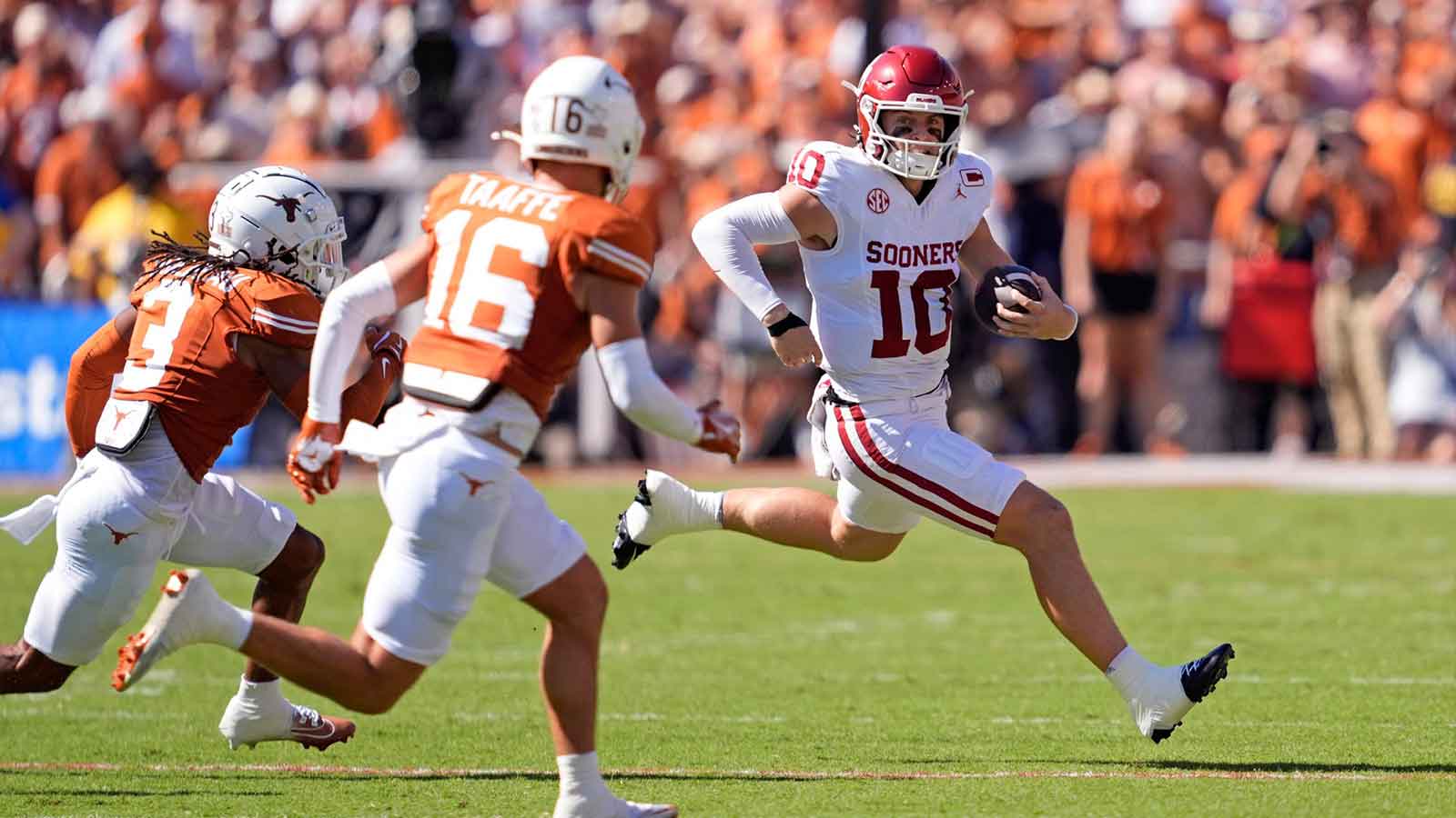 Oklahoma Sooners quarterback John Mateer (10) rushes as Texas Longhorns defensive back Jaylon Guilbeau (3) and Texas Longhorns defensive back Michael Taaffe (16) defend in the first half of the Red River Rivalry college football game between the University of Oklahoma Sooners and the Texas Longhorn at the Cotton Bowl Stadium in Dallas, Texas, Saturday, Oct. 11, 2025.