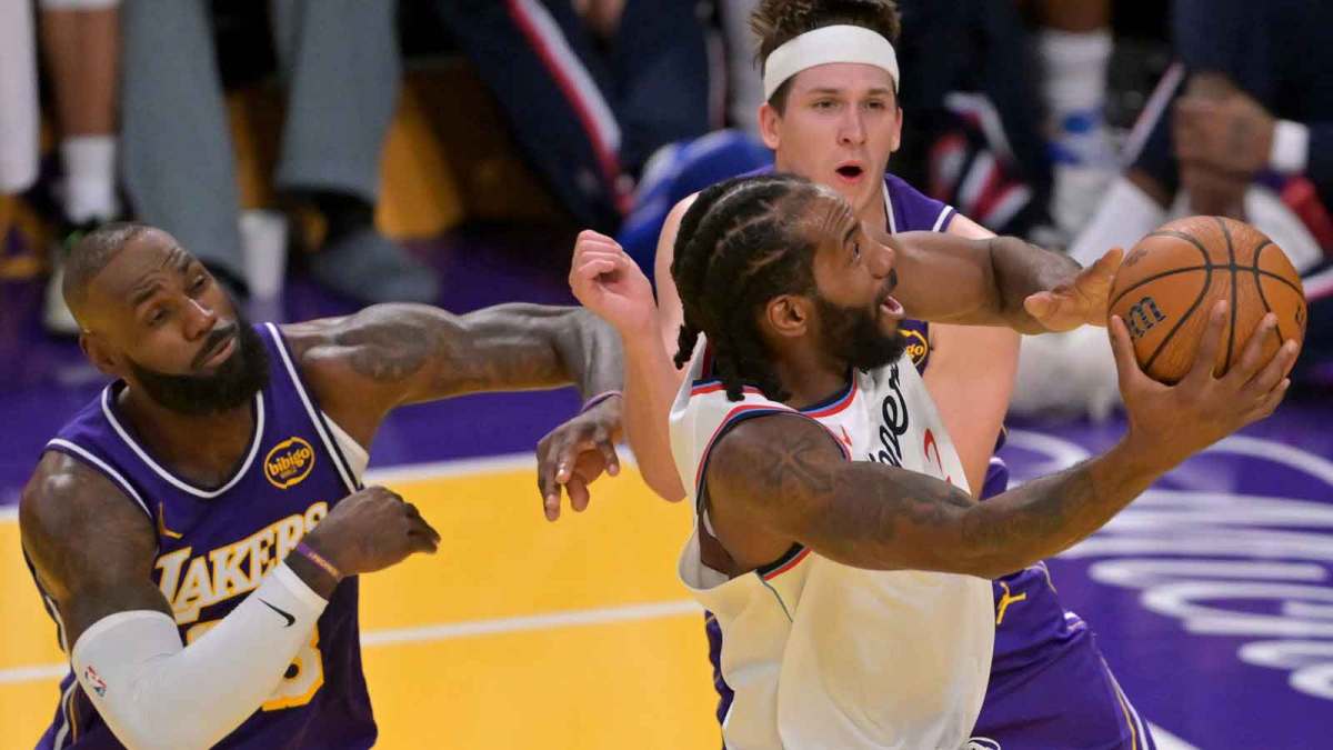 Los Angeles Clippers forward Kawhi Leonard (2) is defended by Los Angeles Lakers forward LeBron James (23) and guard Austin Reaves (15) as he takes a shot in the second half at Crypto.com Arena.