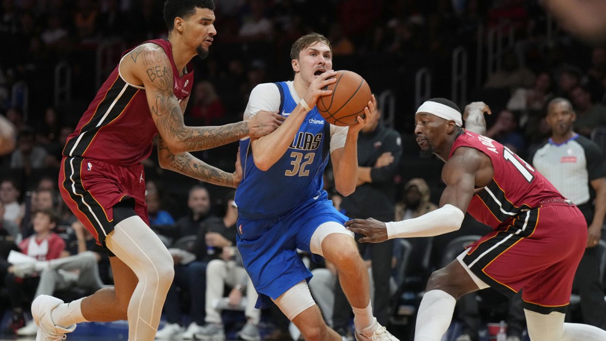 Dallas Mavericks forward Cooper Flagg (32) splits the defense of Miami Heat forward Bam Adebayo (13) and center Kel'el Ware (7) during the second half at Kaseya Center.