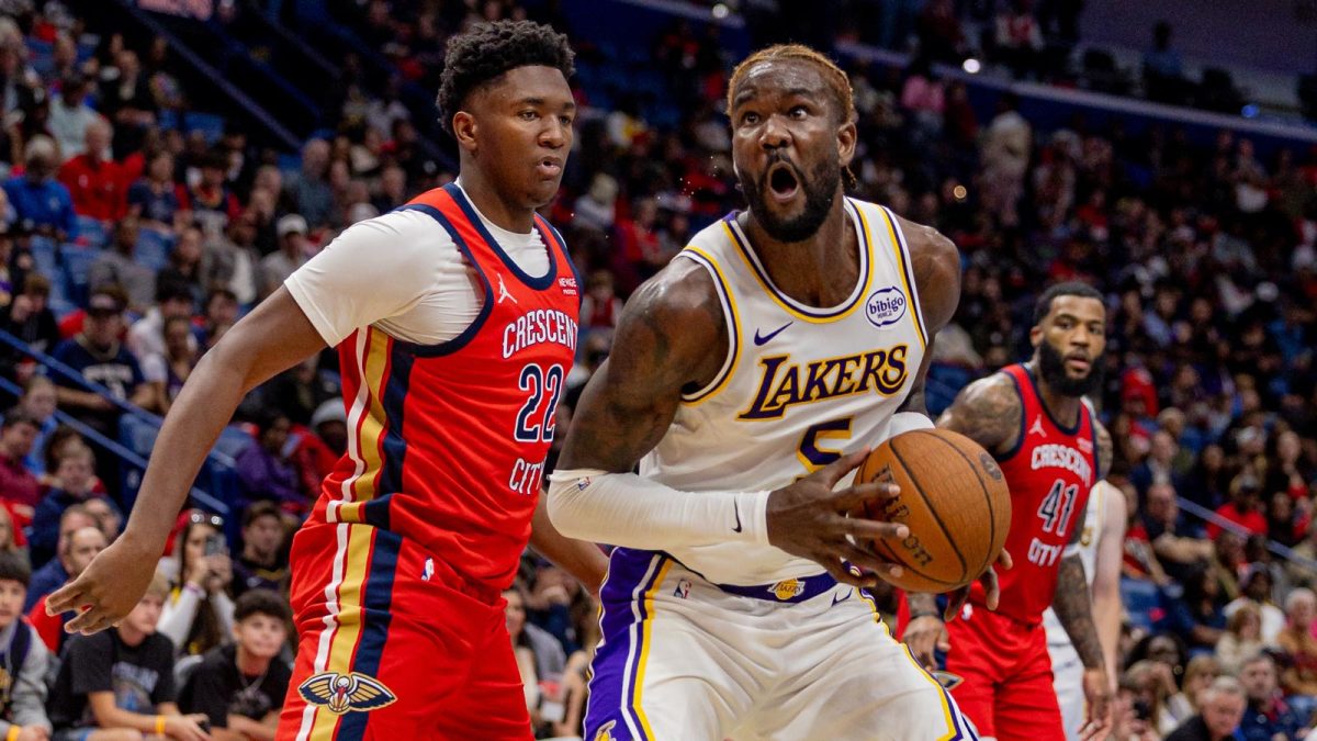 Lakers center Deandre Ayton (5) dribbles against New Orleans Pelicans center Derik Queen (22) during the first half at Smoothie King Center with the Jazz logo in the background