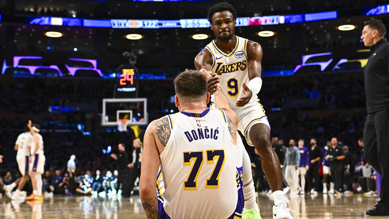 Lakers guard Bronny James (9) helps guard Luka Doncic (77) up from the floor against the Miami Heat during the second half at Crypto.com Arena