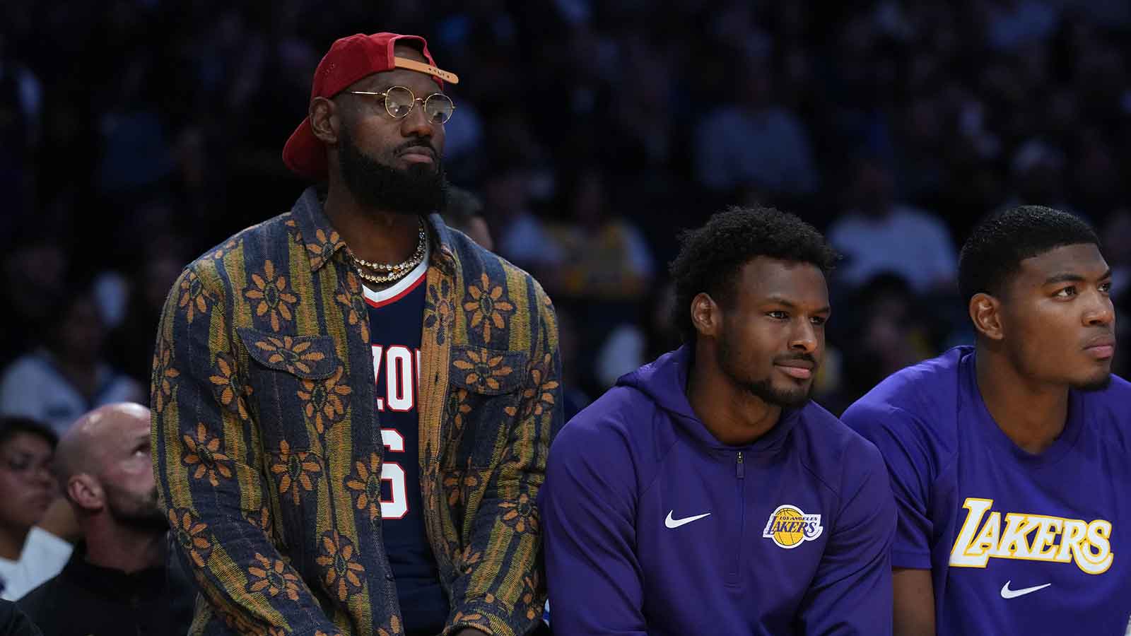 Los Angeles Lakers forward LeBron James (left) and son Bronny James (center) and forward Rui Hachimura (28) watch from the bench in the second half against the Minnesota Timberwolves at Crypto.com Arena.