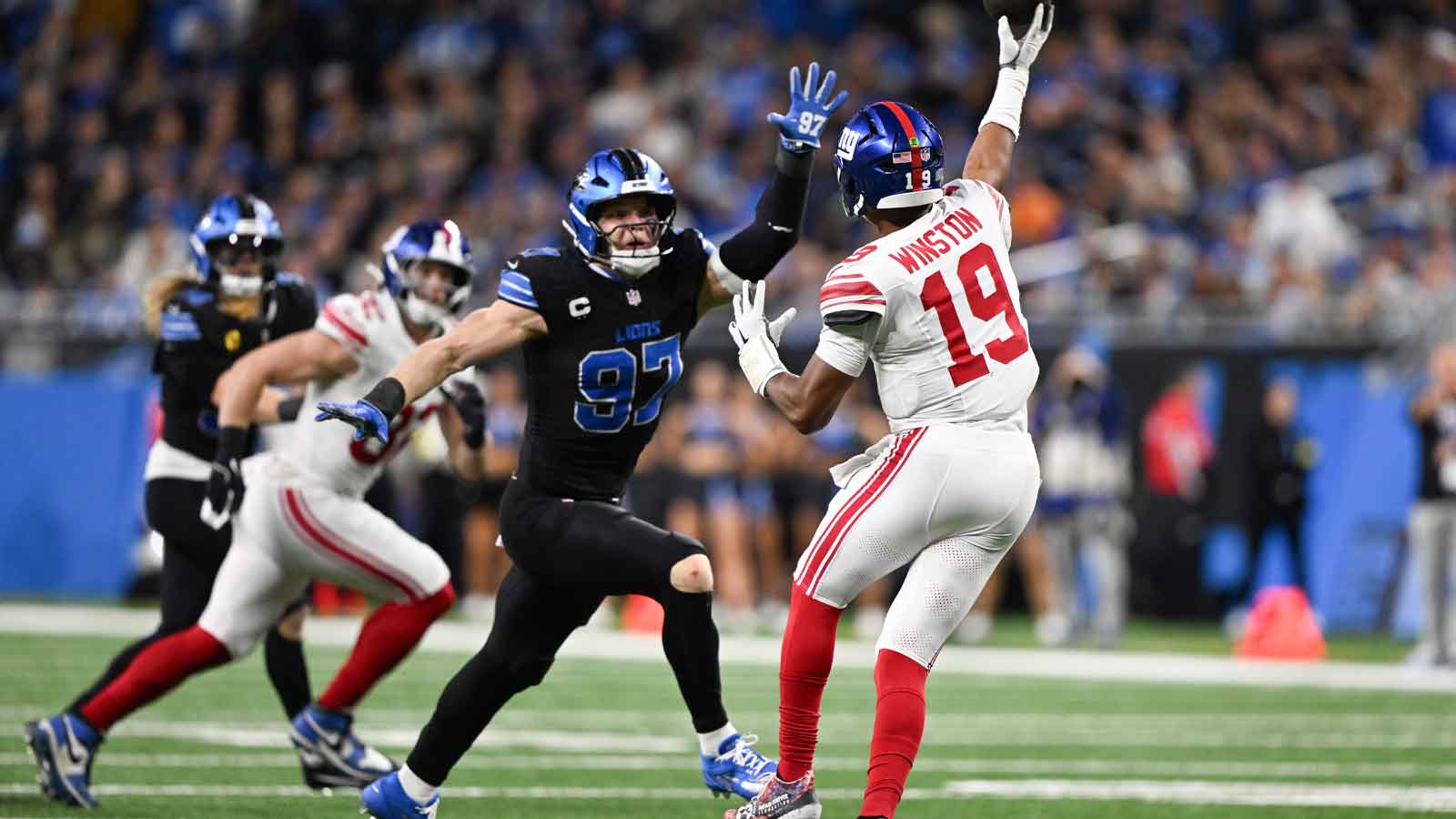 New York Giants quarterback Jameis Winston (19) throws an interception while being defended by Detroit Lions edge Aidan Hutchinson (97) in the fourth quarter at Ford Field.