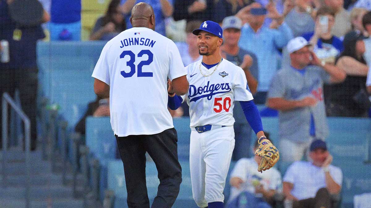 Los Angeles Dodgers shortstop Mookie Betts (50) greets Magic Johnson before game five of the 2025 MLB World Series against the Toronto Blue Jays at Dodger Stadium.