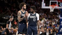 Mavericks forward Naji Marshall (13) is retrained by center Dereck Lively II (2) after Marshall receives a technical foul during the second half against the New Orleans Pelicans at the American Airlines Center with the Grizzlies logo in the background