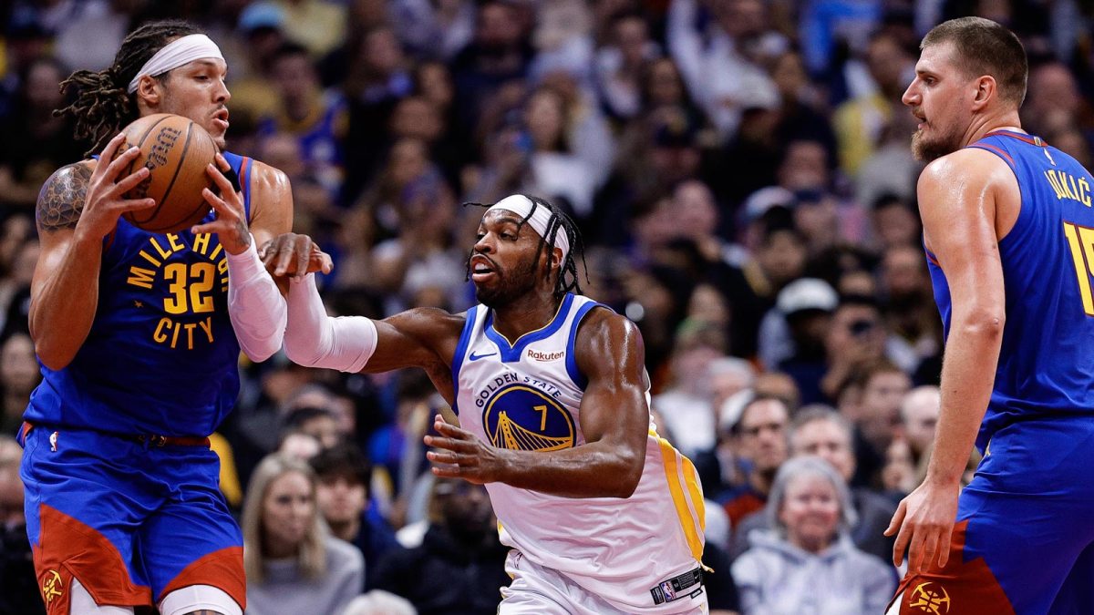 Nuggets forward Aaron Gordon (32) controls the ball under pressure from Golden State Warriors guard Buddy Hield (7) as center Nikola Jokic (15) defends in the first quarter at Ball Arena