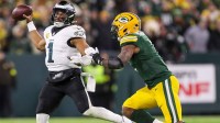 Philadelphia Eagles quarterback Jalen Hurts (1) throws on the run as Green Bay Packers defensive end Micah Parsons closes in.