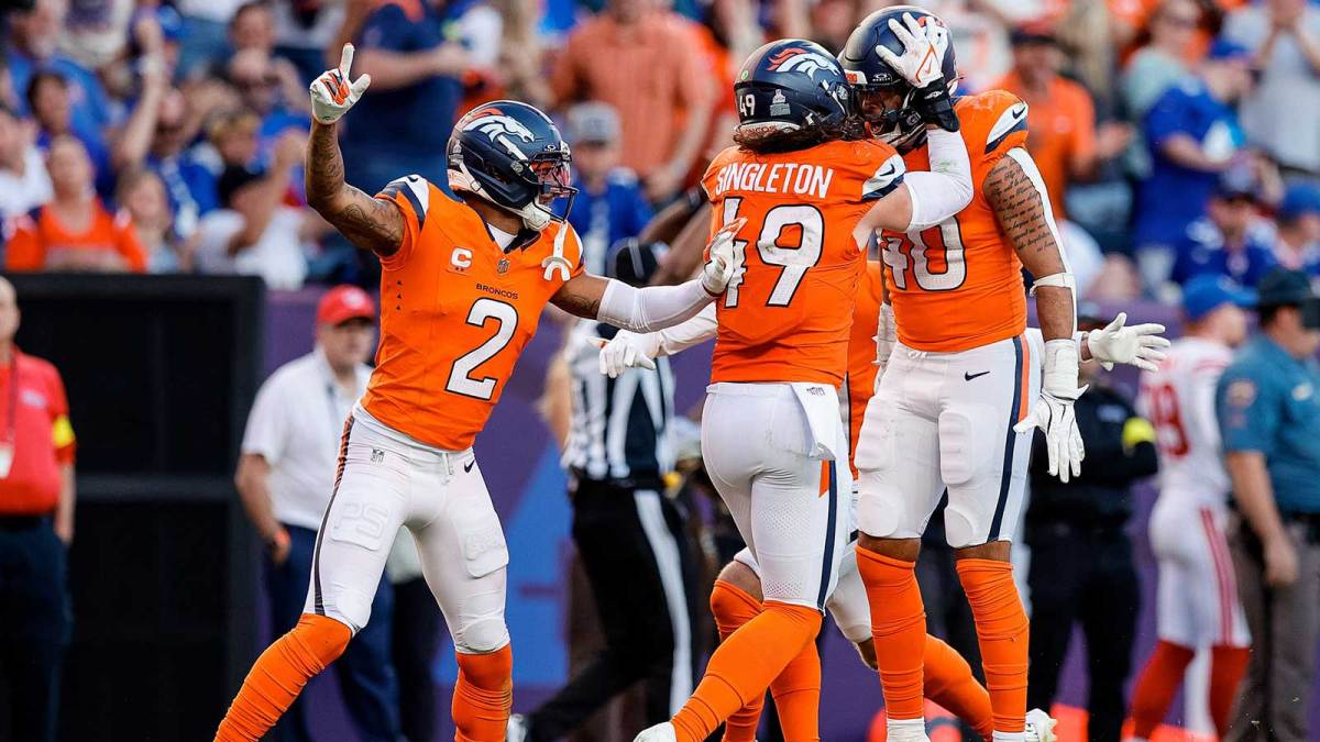 Denver Broncos linebacker Justin Strnad (40) celebrates his interception with linebacker Alex Singleton (49) and cornerback Pat Surtain II (2) in the fourth quarter against the New York Giants at Empower Field at Mile High.