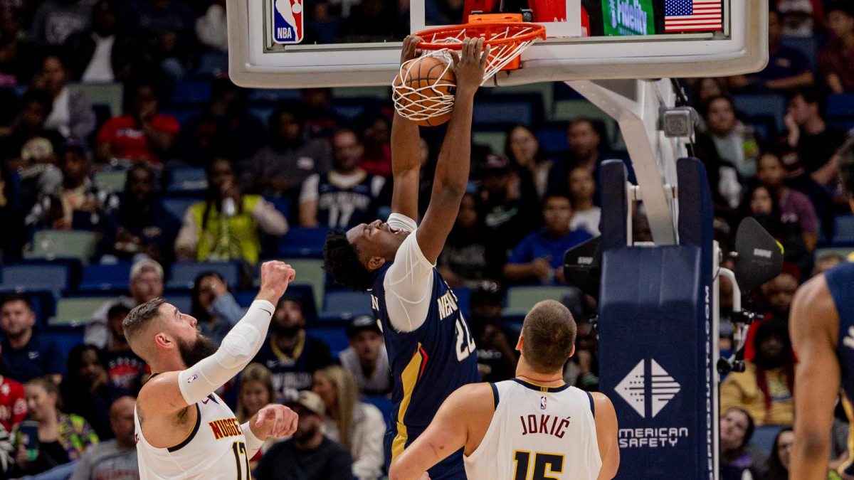 New Orleans Pelicans center Derik Queen (22) dunks the ball against Denver Nuggets center Nikola Jokić (15) and center Jonas Valančiūnas (17) during the first half at Smoothie King Center.