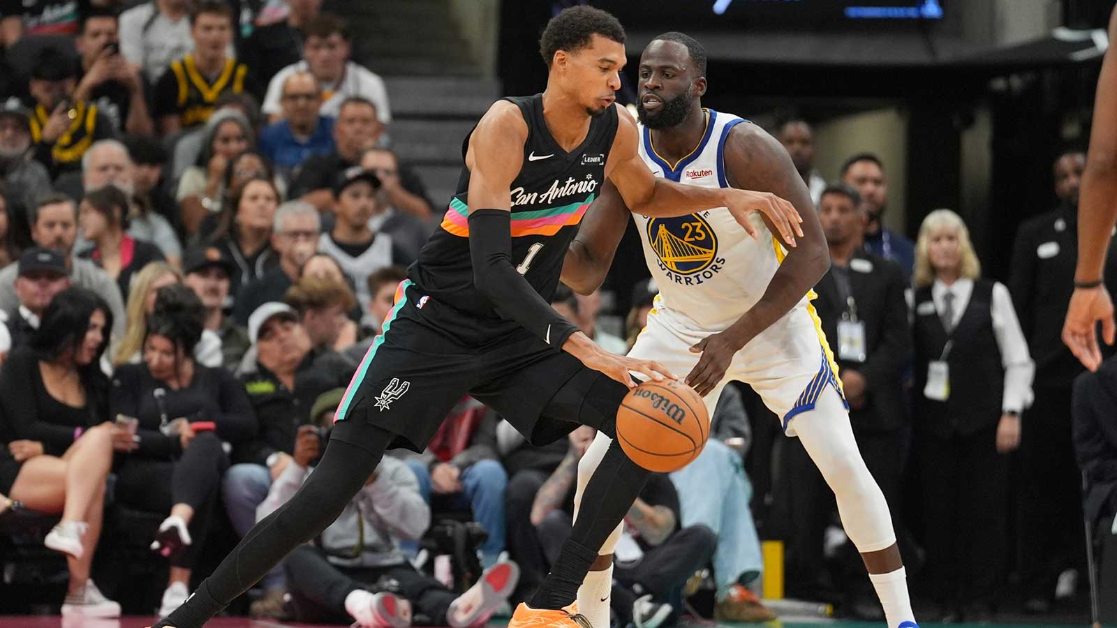 San Antonio Spurs forward Victor Wembanyama (1) dribbles against Golden State Warriors forward Draymond Green (23) in the second half at Frost Bank Center.
