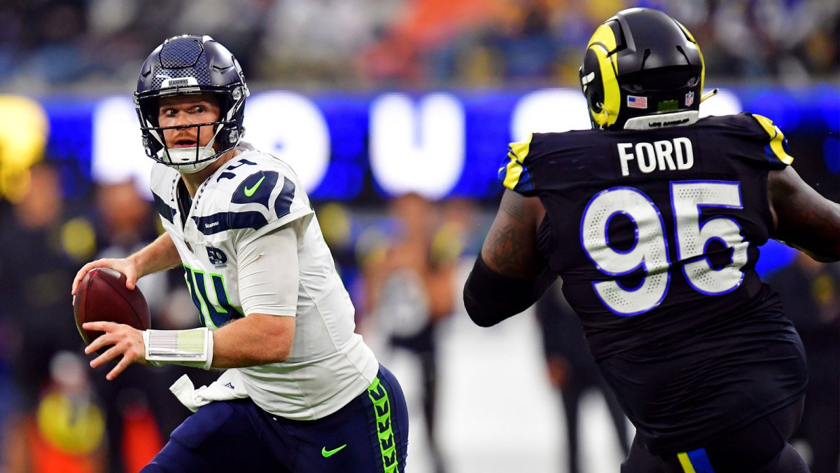 Seattle Seahawks quarterback Sam Darnold (14) rolls out to pass against Los Angeles Rams defensive tackle Poona Ford (95) during the second half at SoFi Stadium.