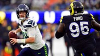 Seattle Seahawks quarterback Sam Darnold (14) rolls out to pass against Los Angeles Rams defensive tackle Poona Ford (95) during the second half at SoFi Stadium.