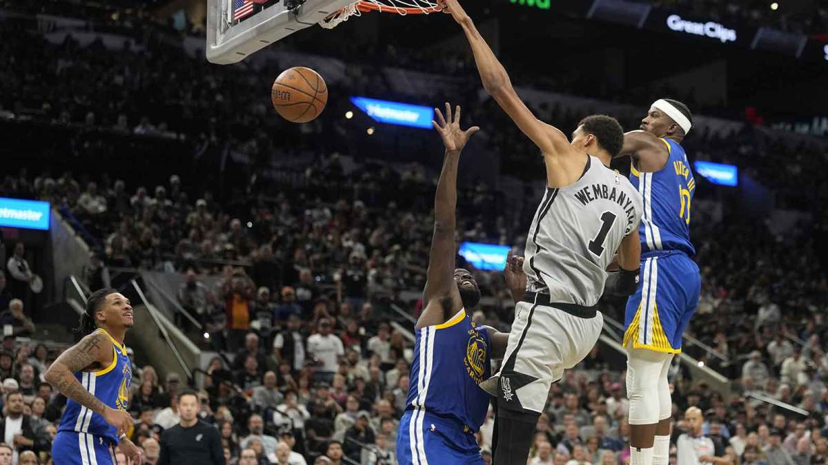 Spurs forward Victor Wembanyama (1) dunks an alley-oop to himself over Golden State Warriors forward Draymond Green (23) ahead of forward Jimmy Butler (10) and guard Will Richard (3) during the second half at Frost Bank Center
