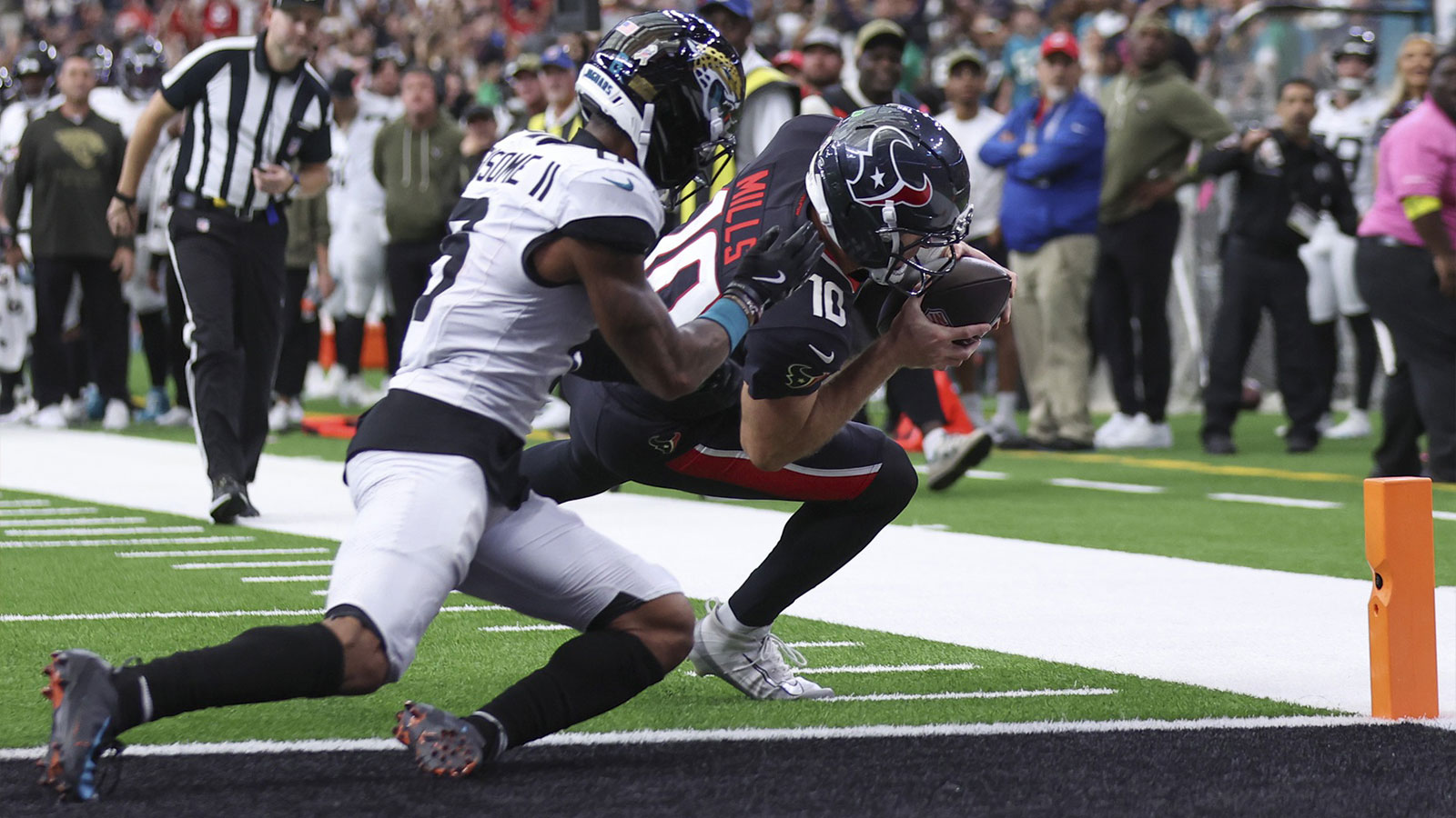 Houston Texans quarterback Davis Mills (10) runs with the ball and scores a touchdown as Jacksonville Jaguars cornerback Greg Newsome II (6) defends during the fourth quarter at NRG Stadium.