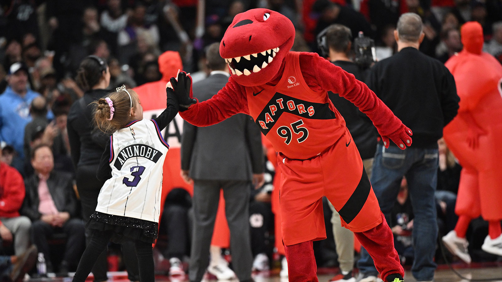 The Toronto Raptors mascot slaps hands with a young fan during a timeout against the Brooklyn Nets at Scotiabank Arena. 