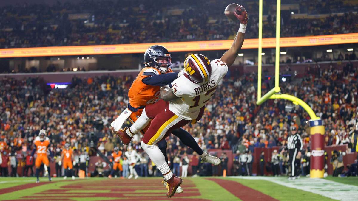 Washington Commanders wide receiver Treylon Burks (13) makes a catch for a touchdown defended by Denver Broncos cornerback Riley Moss (21) in the third quarter of the game at Northwest Stadium.