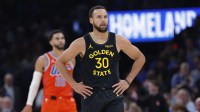 Warriors guard Stephen Curry (30) stands a play against the Oklahoma City Thunder during the second half at Paycom Center with Thunder's Ajay Mitchell and head coach Mark Daigneault in the background