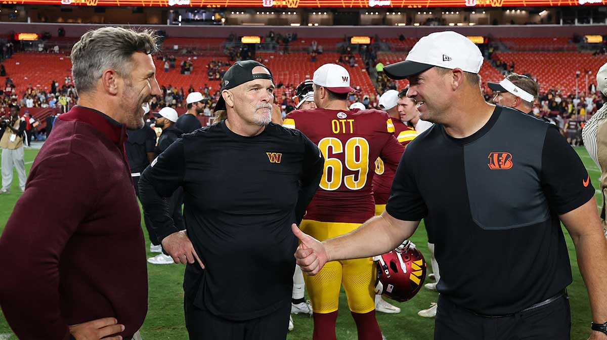 (L-R) Washington Commanders general manager Adam Peters, Commanders head coach Dan Quinn, and Cincinnati Bengals head coach Zac Taylor talk on the field after their game at Northwest Stadium.
