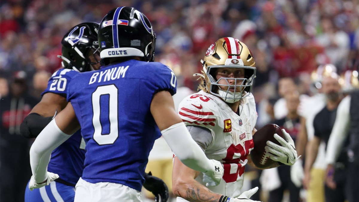 San Francisco 49ers tight end George Kittle (85) carries the ball defended by Indianapolis Colts safety Nick Cross (20) and safety Cam Bynum (0) in the third quarter of the game at Lucas Oil Stadium.