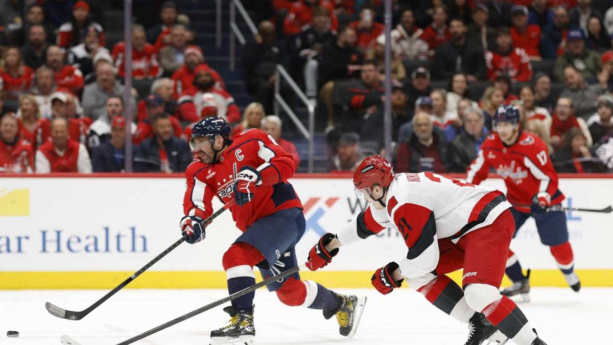 Washington Capitals left wing Alex Ovechkin (8) shoots the puck as Carolina Hurricanes defenseman Alexander Nikishin (21) defends during the third period at Capital One Arena.
