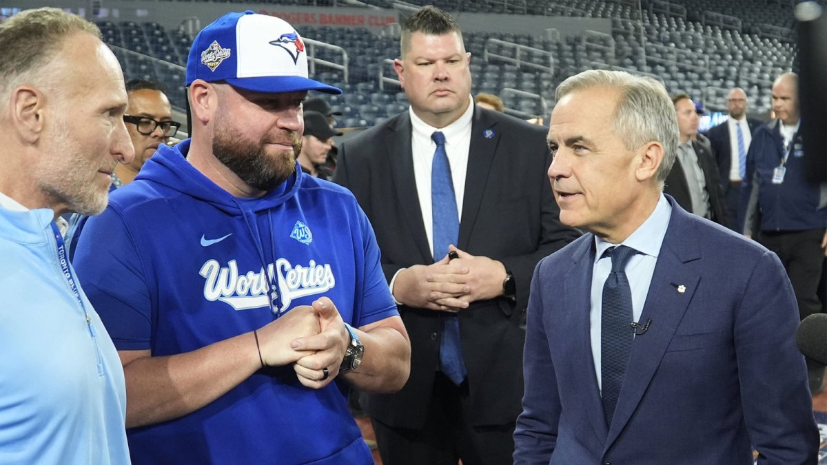Toronto Blue Jays President and CEO Mark Shapiro (left) and manager John Schneider (center) listen to Canadian Prime Minister Mark Carney during media day before game one of the World Series against the Los Angeles Dodgers at Rogers Centre.