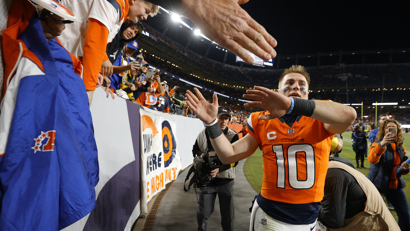 Denver Broncos quarterback Bo Nix (10) high-fives fans following a win over the Green Bay Packers at Empower Field at Mile High.