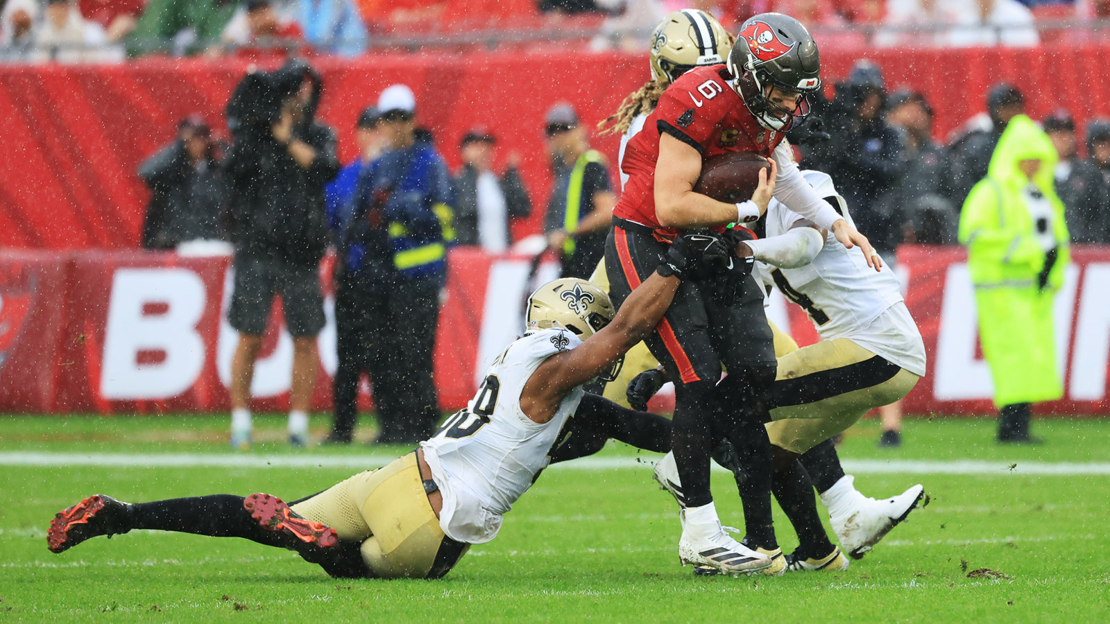 Tampa Bay Buccaneers quarterback Baker Mayfield (6) is tackled by New Orleans Saints linebacker Demario Davis (56) and cornerback Kool-Aid McKinstry (4) during the second quarter at Raymond James Stadium.