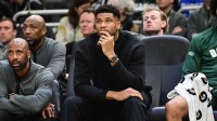 Bucks forward Giannis Antetokounmpo (34) looks on from the bench while recovering from an injury in the second quarter against the Boston Celtics at Fiserv Forum with ESPN's Kendrick Perkins in the background