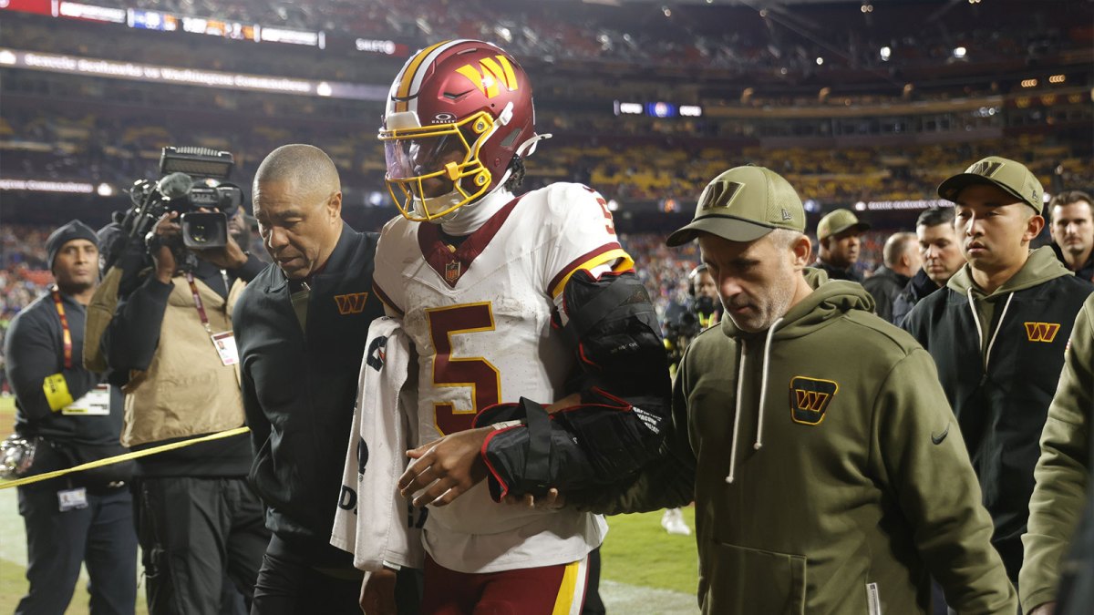 Washington Commanders quarterback Jayden Daniels (5) is helped off the field after an injury during the second half against the Seattle Seahawks at Northwest Stadium.