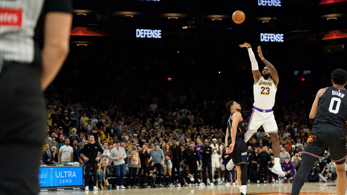 Phoenix Suns guard Devin Booker (1) is called for a foul against Los Angeles Lakers forward LeBron James (23) from behind the three point line during the second half of the game at Mortgage Matchup Center.