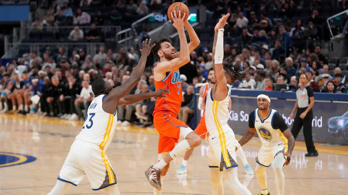 Oklahoma City Thunder center Chet Holmgren (7) shoots the ball between Golden State Warriors forward Draymond Green (23) and guard Will Richard (3) in the third quarter at the Chase Center.