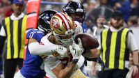 San Francisco 49ers tight end George Kittle (85) carries the ball defended by Indianapolis Colts safety Nick Cross (20) and safety Cam Bynum (0) in the third quarter of the game at Lucas Oil Stadium.