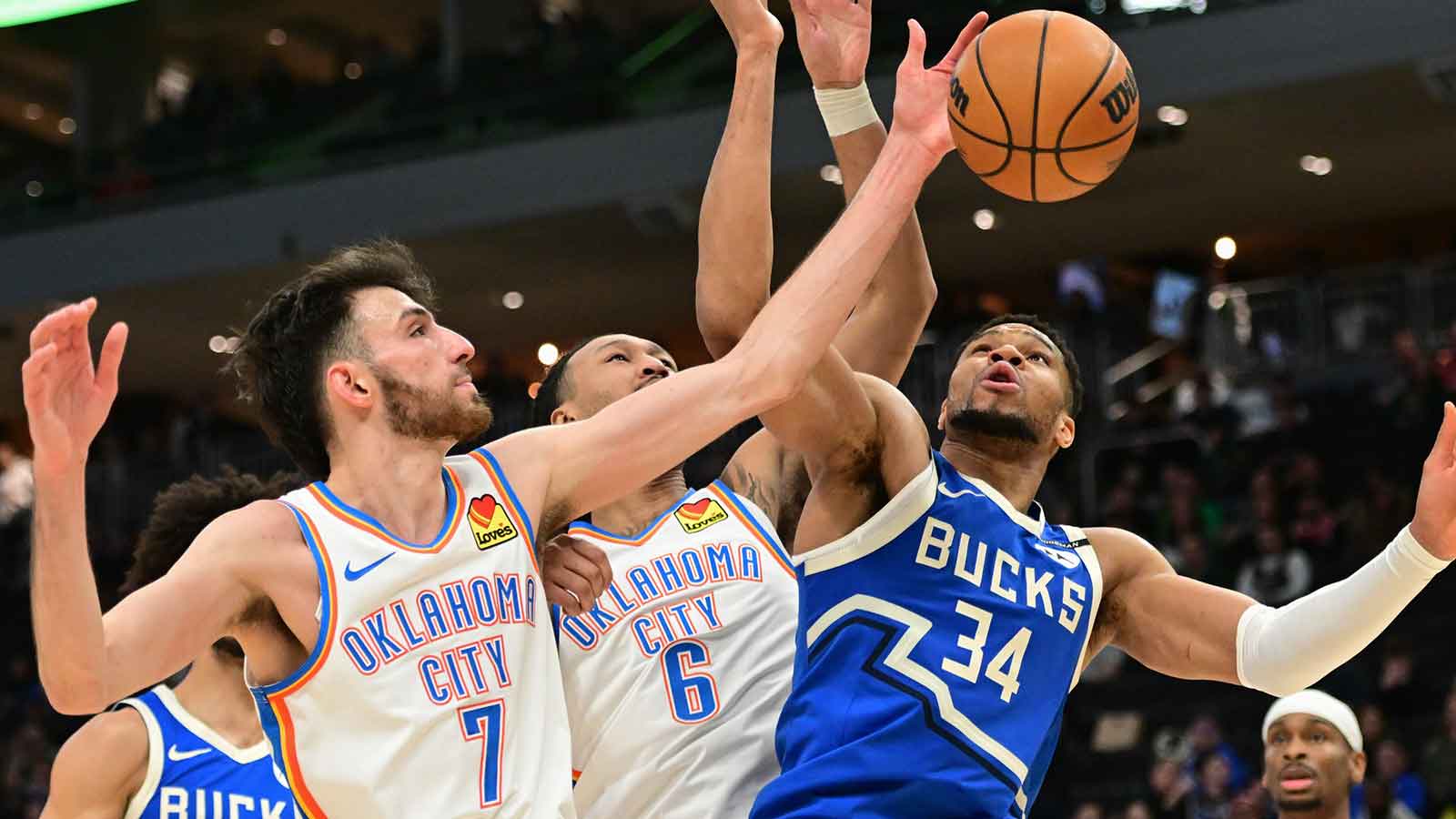Milwaukee Bucks forward Giannis Antetokounmpo (34) reaches for the ball against Oklahoma City Thunder center Chet Holmgren (7) and forward Jaylin Williams (6) in the fourth quarter at Fiserv Forum.