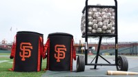 Ball bags with the San Francisco Giants logo sit on the field with a ball cart before the game against the Tampa Bay Rays at Oracle Park.