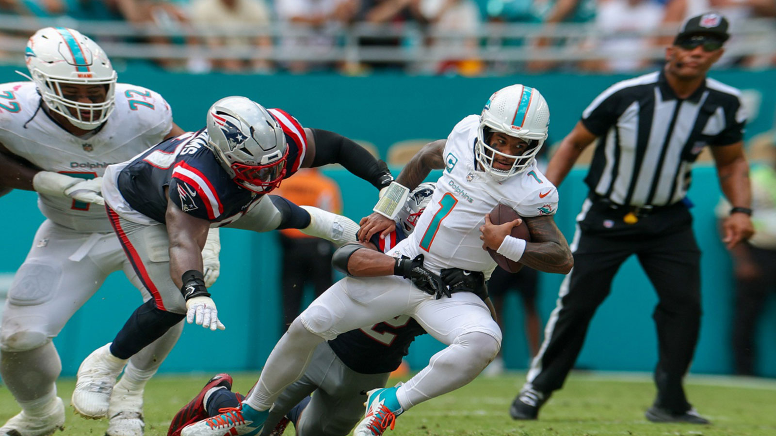 Miami Dolphins quarterback Tua Tagovailoa (1) is tailed by New England Patriots linebacker Harold Landry III (2) in the fourth quarter at Hard Rock Stadium. 