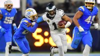 Philadelphia Eagles quarterback Jalen Hurts (1) runs against Los Angeles Chargers cornerback Donte Jackson (26) in overtime at SoFi Stadium.