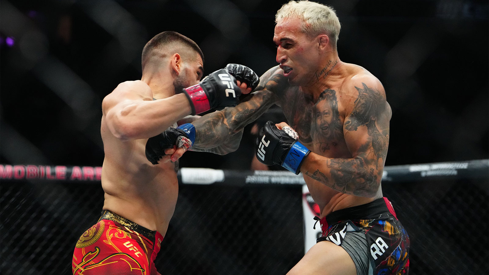 Ilia Topuria (red gloves) fights Charles Oliveira (blue gloves) during UFC 317 at T-Mobile Arena.