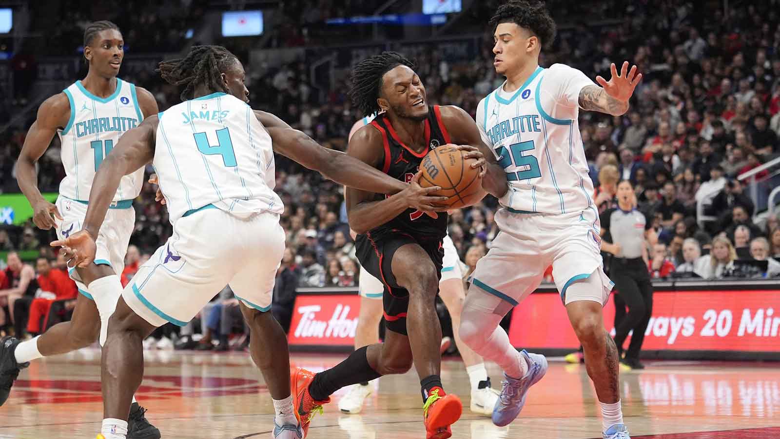 Toronto Raptors guard Immanuel Quickley (5) dribbles the ball past Charlotte Hornets guard Sion James (4) and guard KJ Simpson (25) during the first half at Scotiabank Arena.