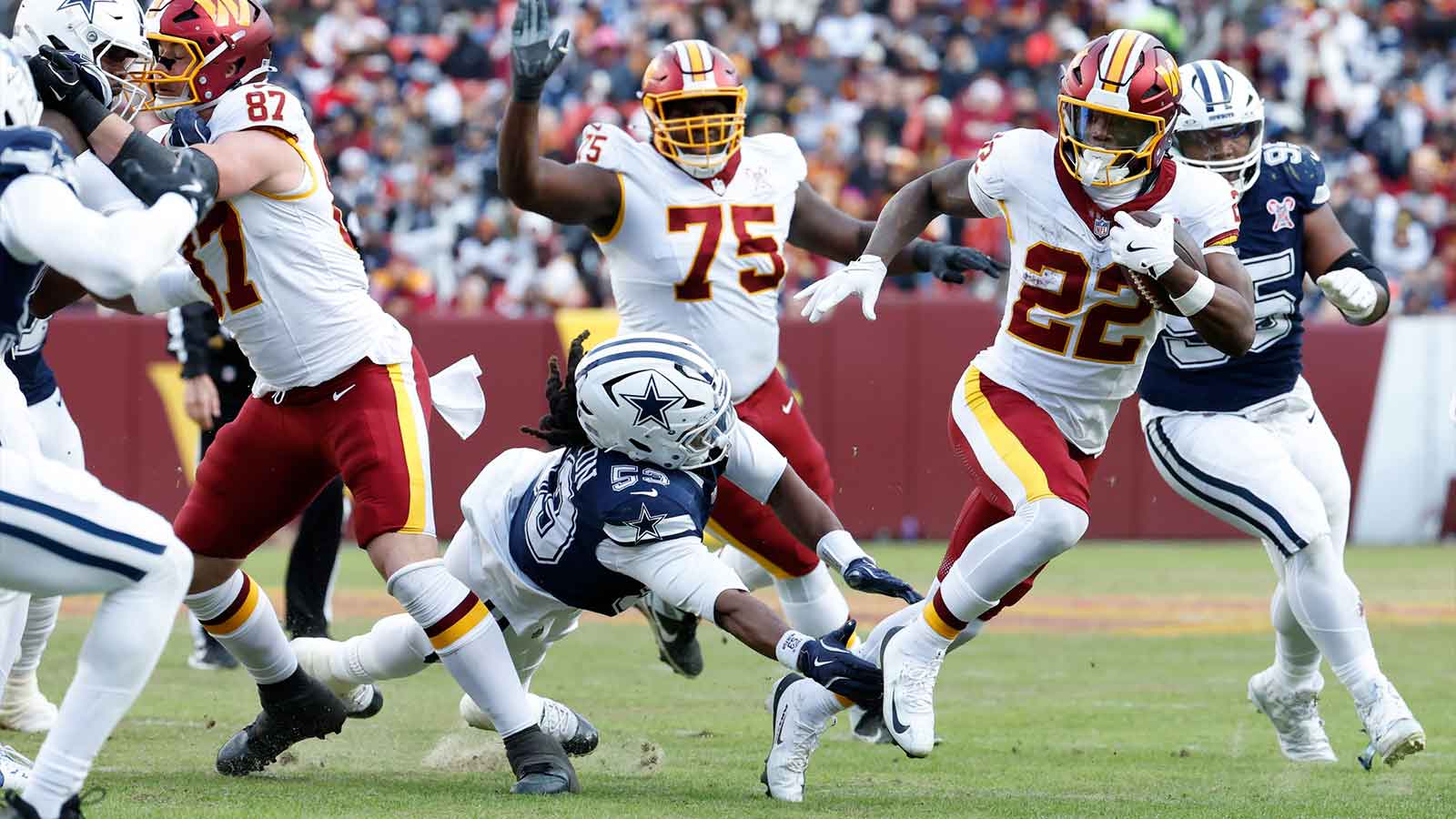 Washington Commanders running back Jacory Croskey-Merritt (22) carries the ball defended by Dallas Cowboys defensive end James Houston (53) in the third quarter at Northwest Stadium.