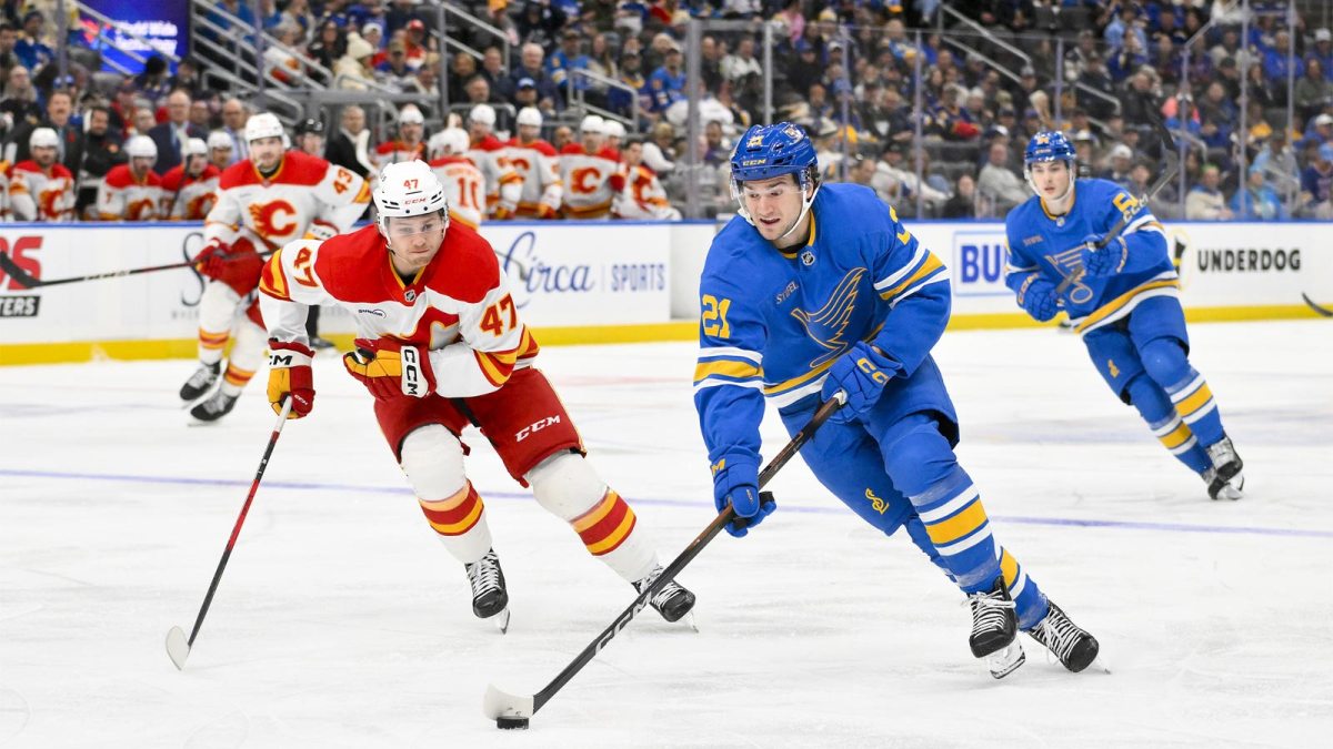 St. Louis Blues right wing Jimmy Snuggerud (21) controls the puck as Calgary Flames center Connor Zary (47) defends during the second period at Enterprise Center.