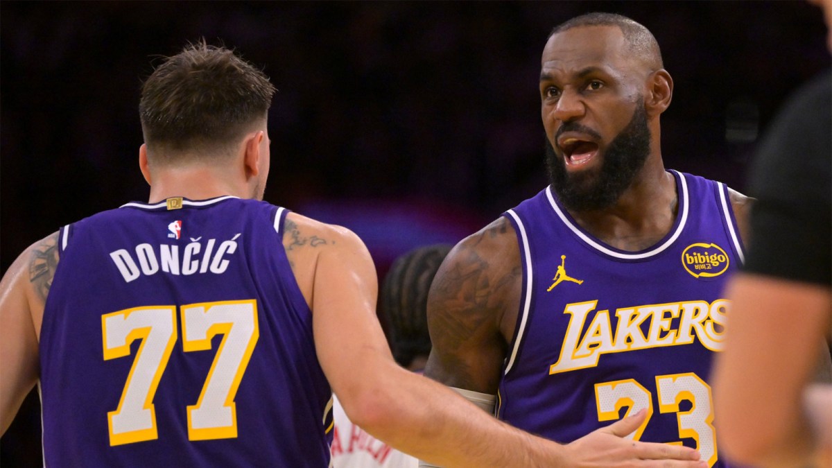 Lakers guard Luka Doncic (77) and forward LeBron James (23) react after a foul during the first half against the Los Angeles Clippers at Crypto.com Arena with the Suns logo in the background